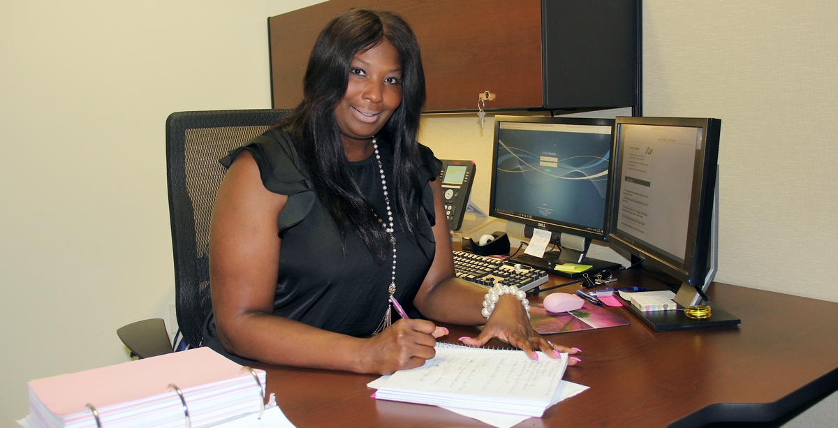 Contracts Supervisor Monica Moye sitting at her desk and writing something in her notebook.